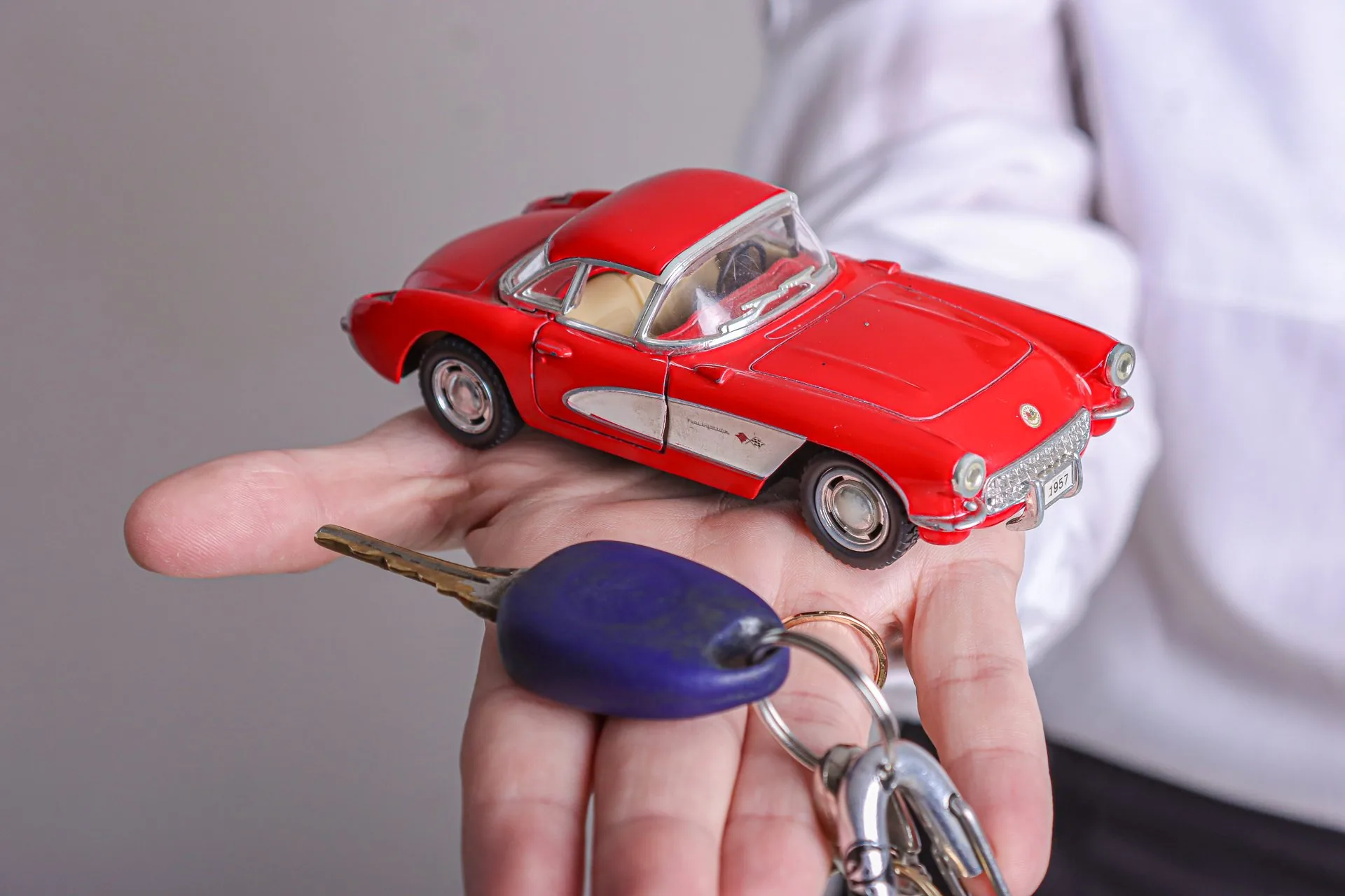 Mão segurando carrinho vermelho e chaves de carro — financiamento de veículos AP Financeira